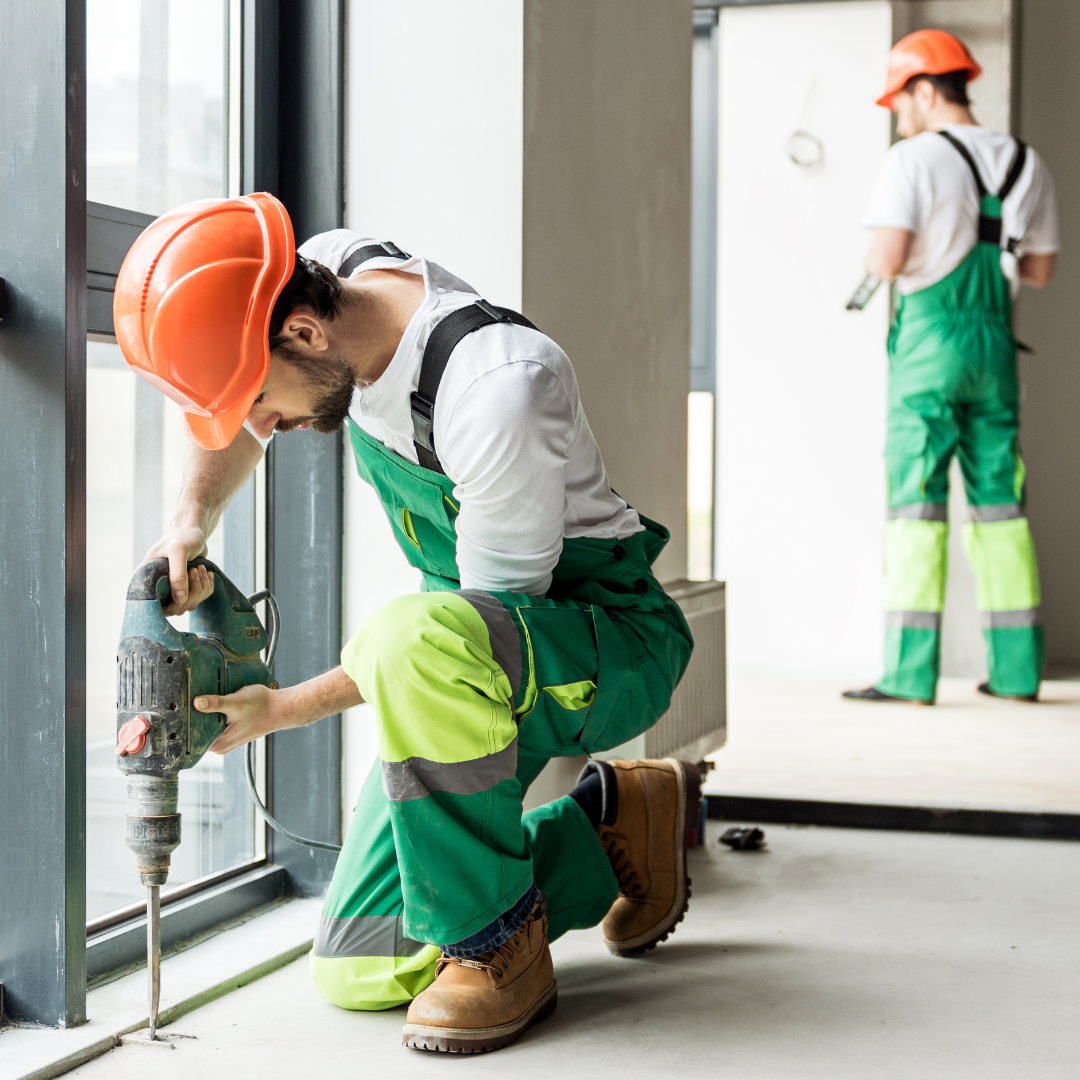 A person in green overalls holding a drill

Description automatically generated